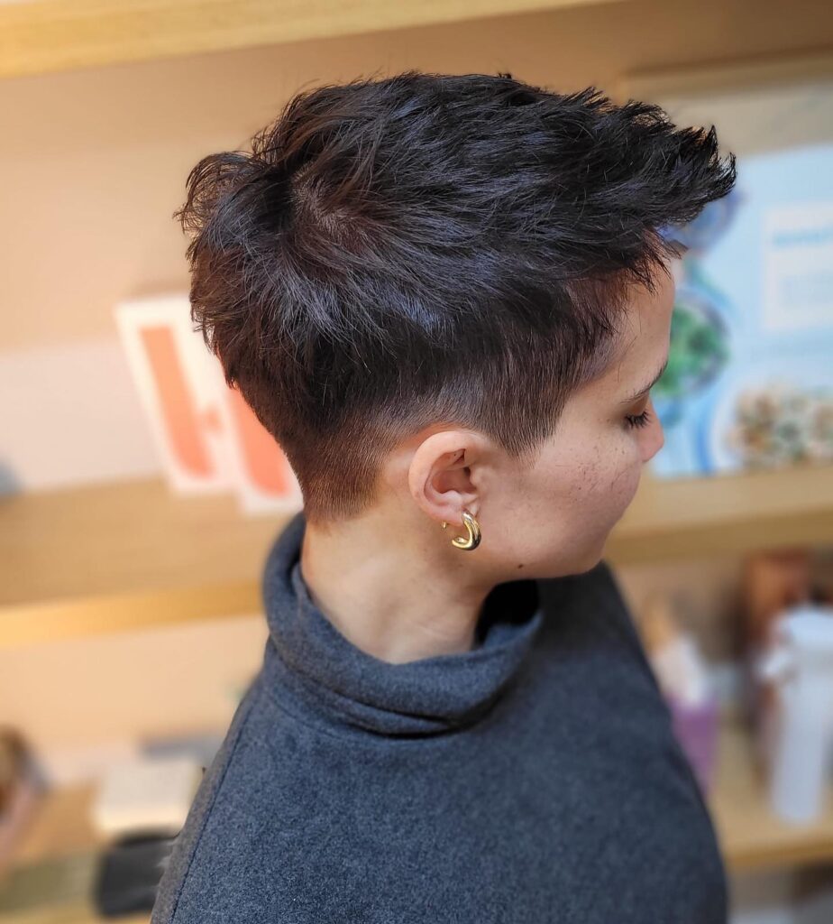 A woman with a tapered tomboy haircut featuring short sides and a softly layered longer top in dark brown.