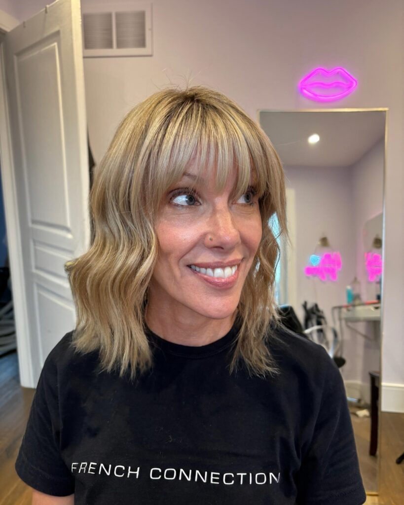 Blonde wavy bob with soft layers and wispy bangs.