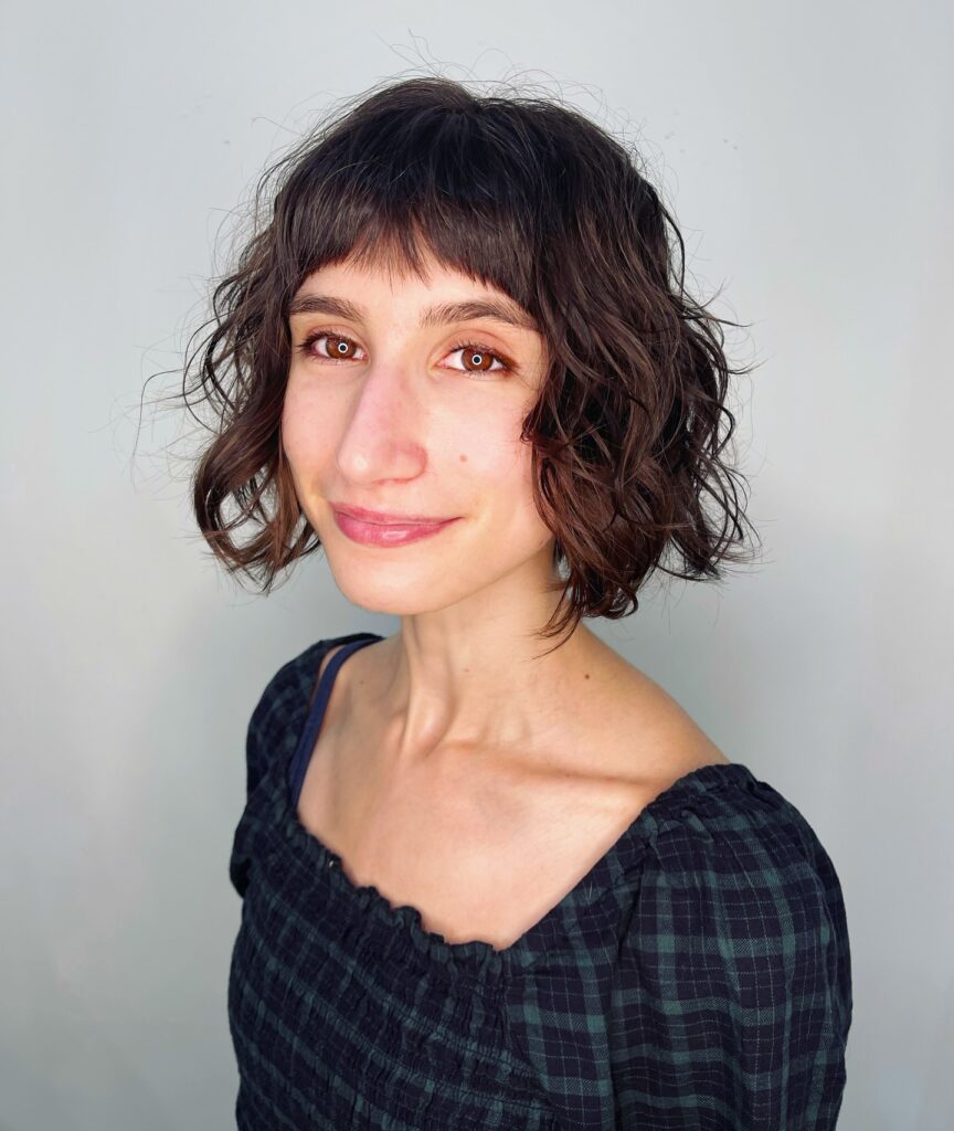 Short curly brown bob with choppy layers and a micro fringe.