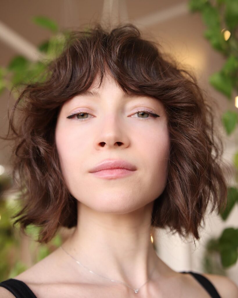 Short curly brown bob with soft texture and a wispy fringe.