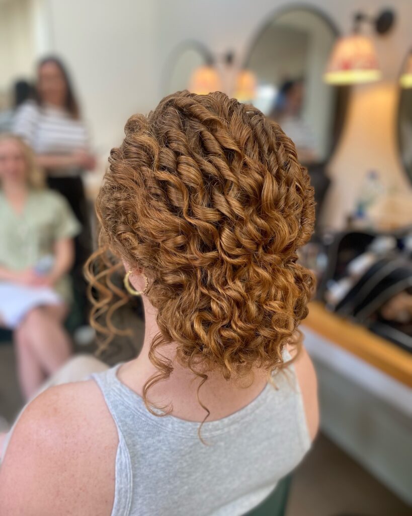 A twisted curly updo with defined ringlets styled into a neat low bun.