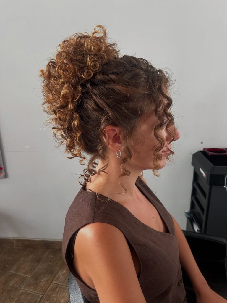A romantic curly updo with soft volume and loose ringlets framing the face.