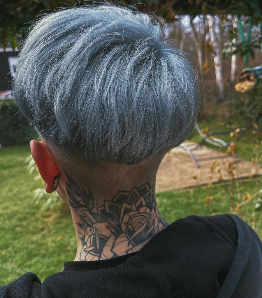 A woman with a short silver tomboy haircut featuring a rounded top and an undercut nape.
