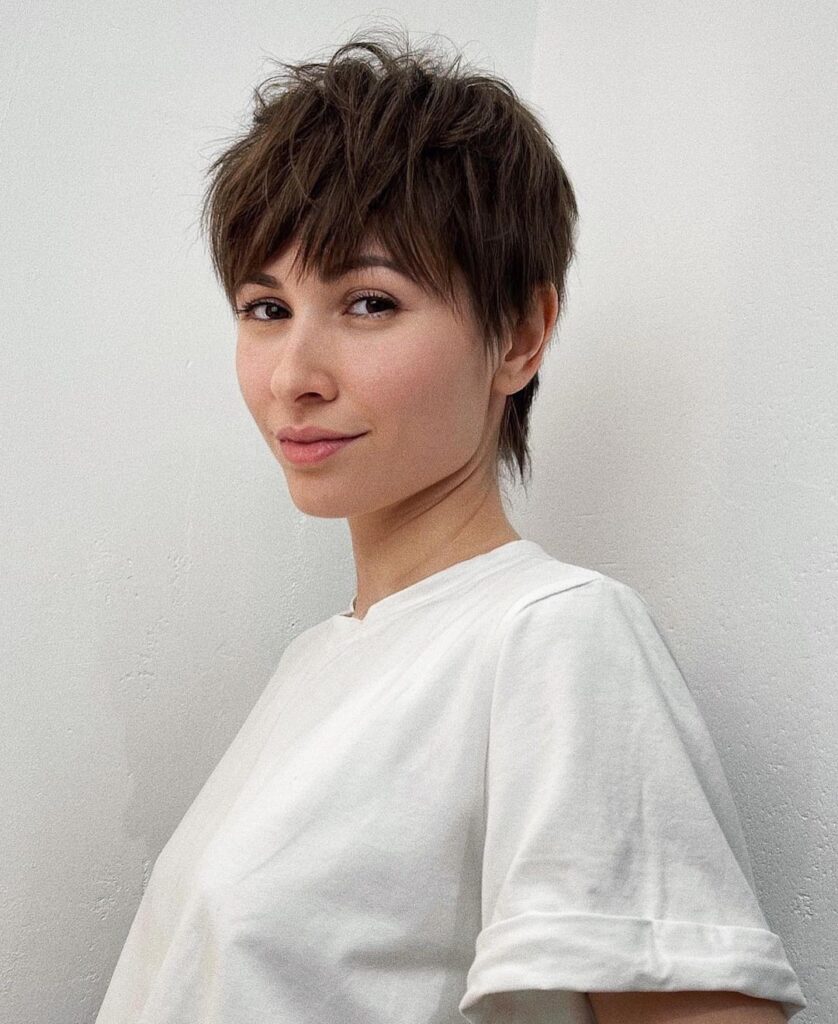 A woman with a short layered tomboy pixie haircut with soft texture and a feathered fringe.