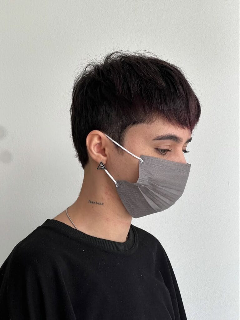 A woman with a sleek short tomboy pixie haircut featuring cropped sides and a smooth dark brown top.