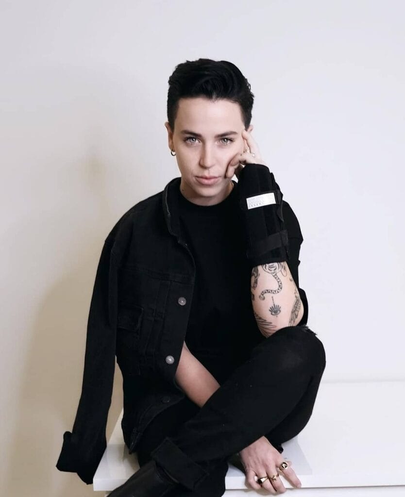 A woman with a sleek back tomboy crop haircut featuring short sides and a smooth styled black top.