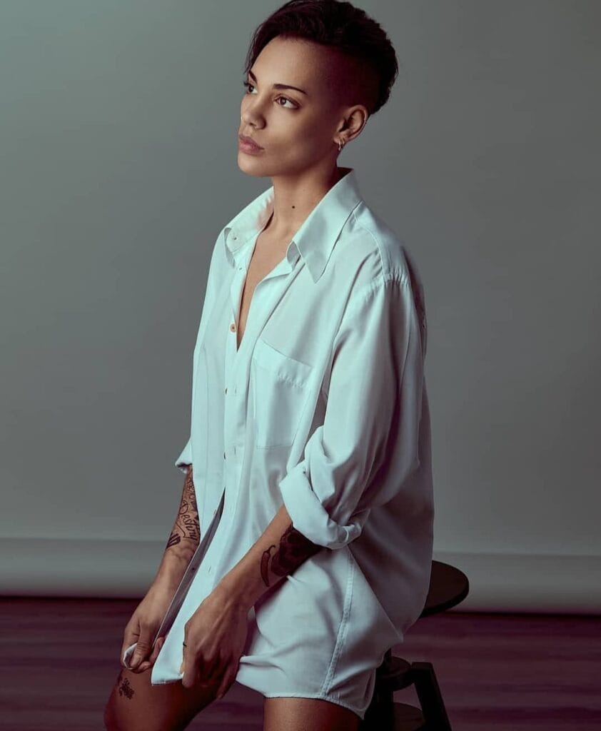A woman with a bold undercut tomboy hairstyle featuring shaved sides and a longer swept back top in dark hair.