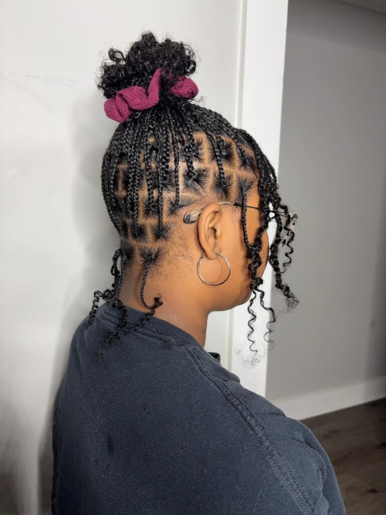 Star parted braided natural hairstyle styled into a curly bun with loose tendrils