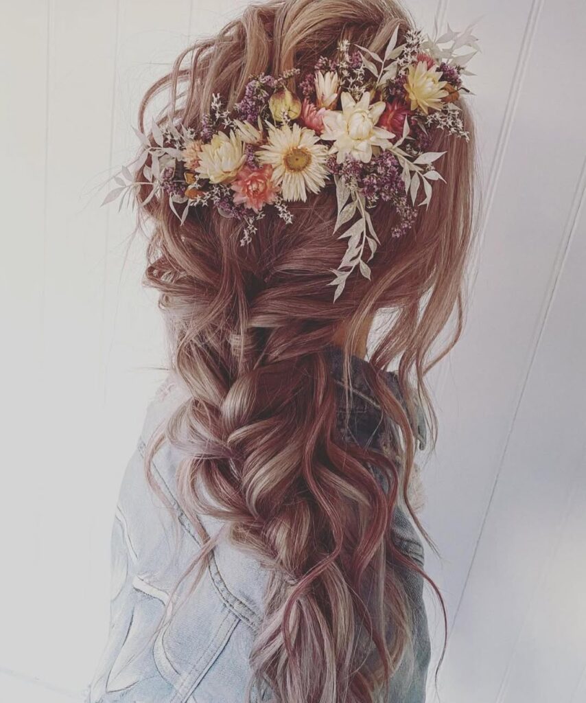 Long wavy hair styled in a loose braid with a floral crown in a romantic boho style.
