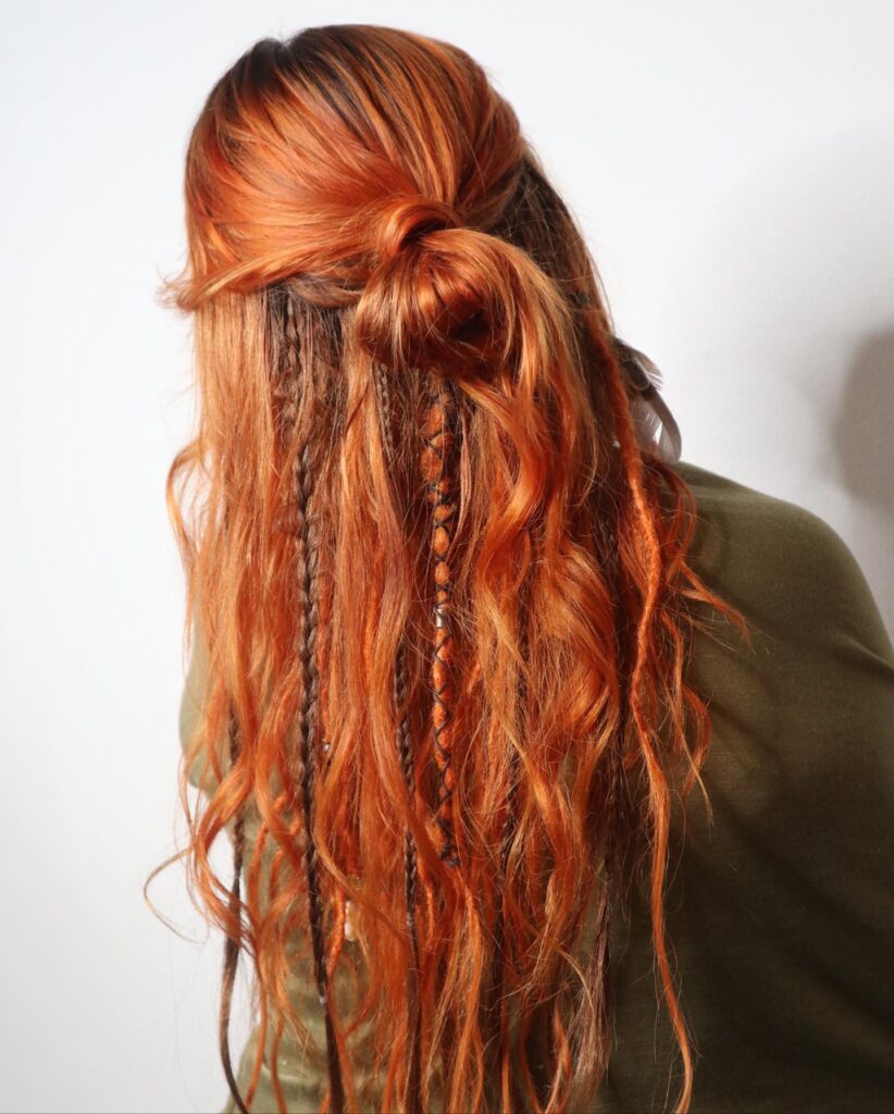Long copper red wavy hair with thin braids throughout in a relaxed boho style.