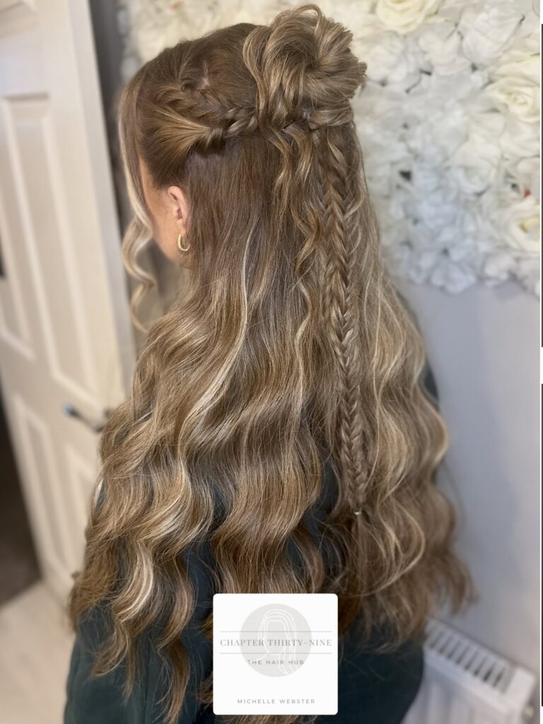 Long brown wavy hair styled in a half up bun with a thin braid detail.