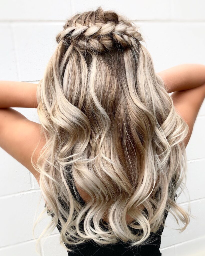 Long blonde curly hair styled with a crown braid and loose beachy waves.