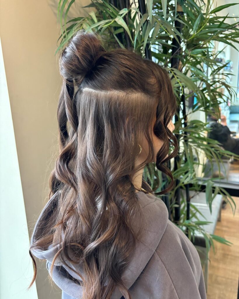 Long wavy hair styled with a small half up bun and loose curls flowing down.