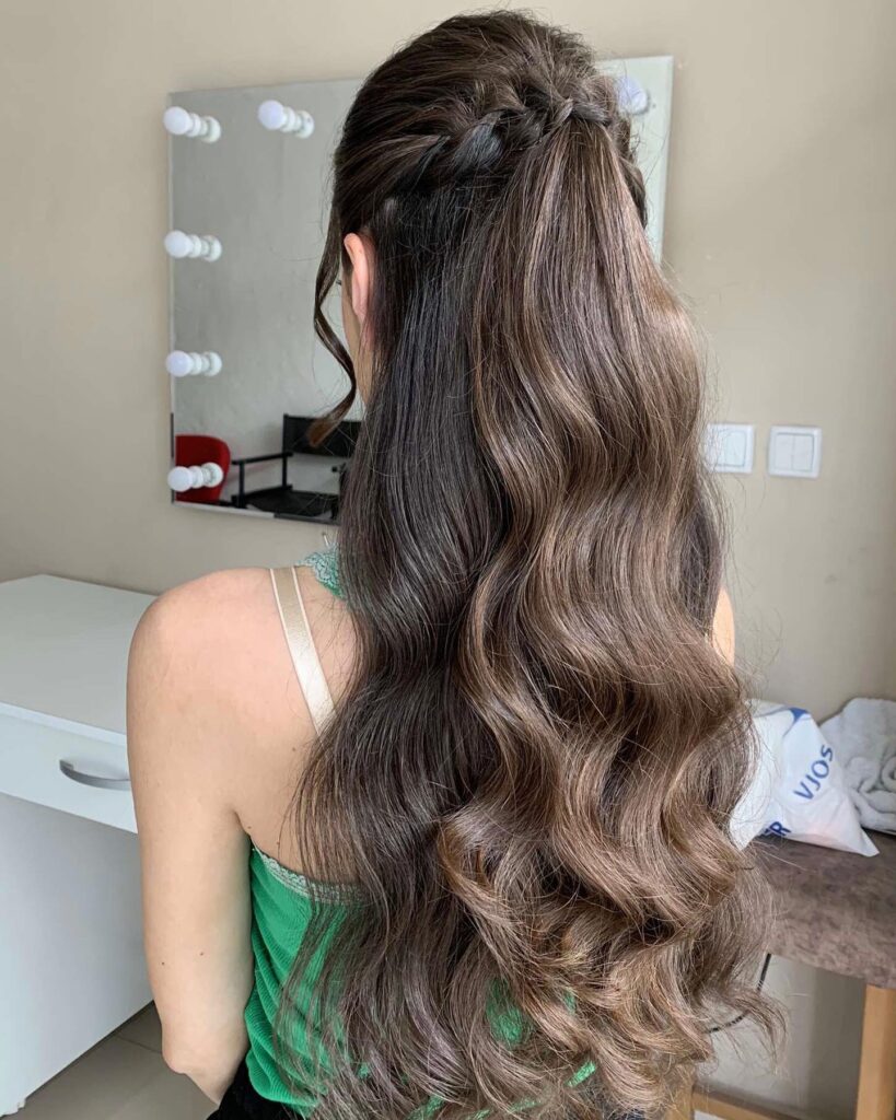 Long wavy brunette hair styled in a half up twisted hairstyle with volume at the crown.