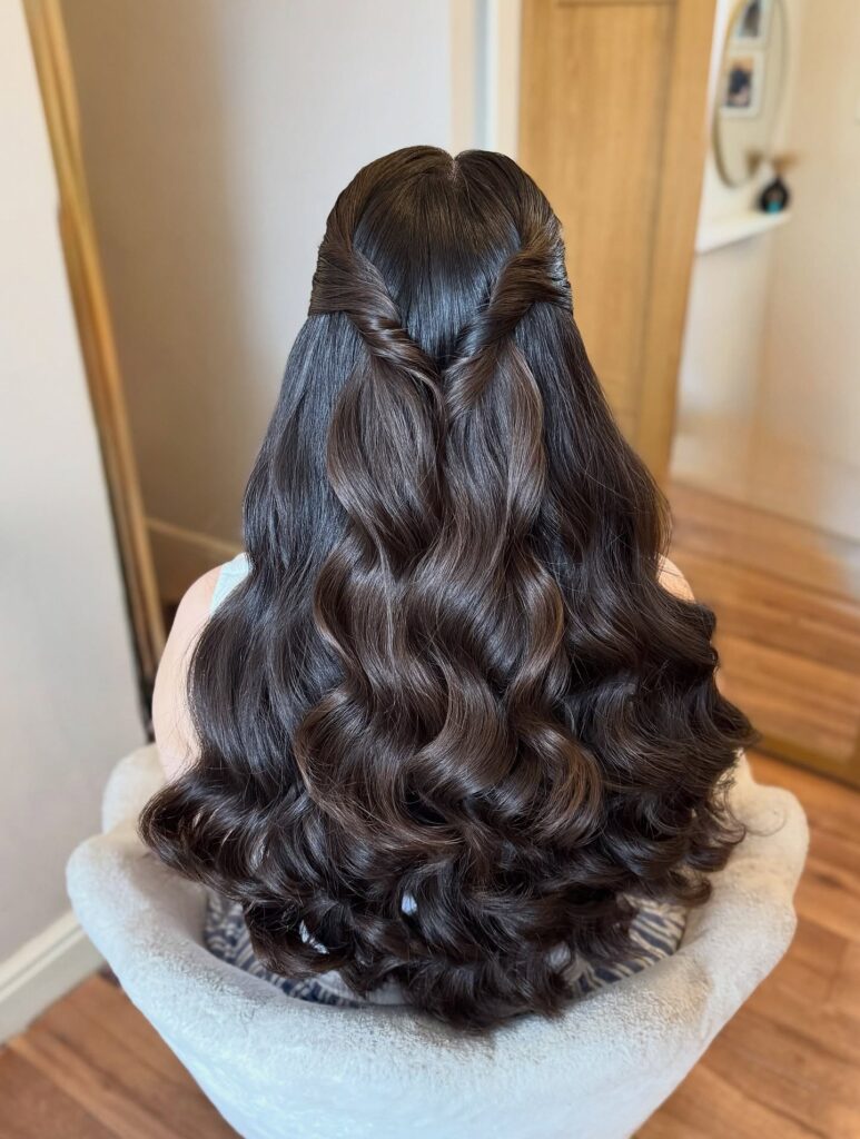 Long dark curly hair styled in a twisted half up look with soft flowing curls.