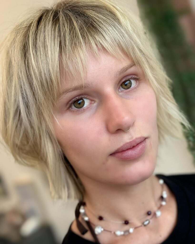 A soft blonde textured bob with wispy bangs and a light airy finish.