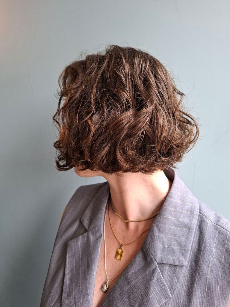 A woman with a rounded medium brown curly bob that has soft structure and natural curl definition.