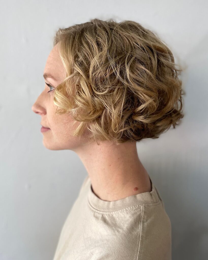 A short blonde curly bob with soft layers and a light airy texture.