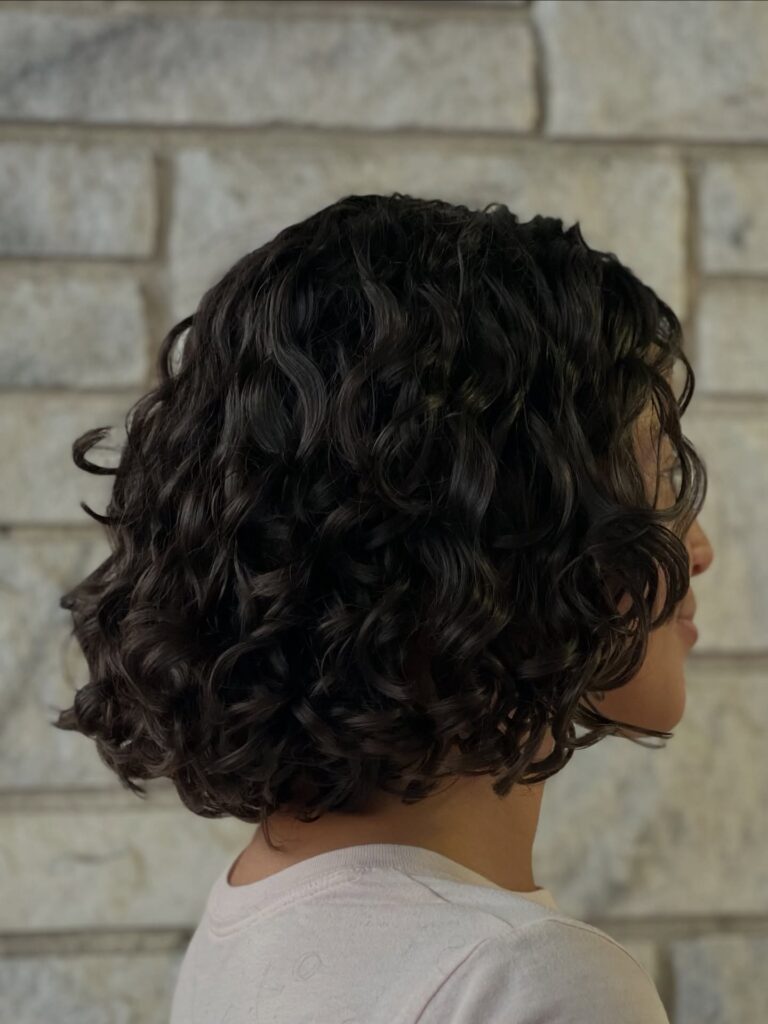 A chin length dark curly bob with defined curls and a rounded shape.