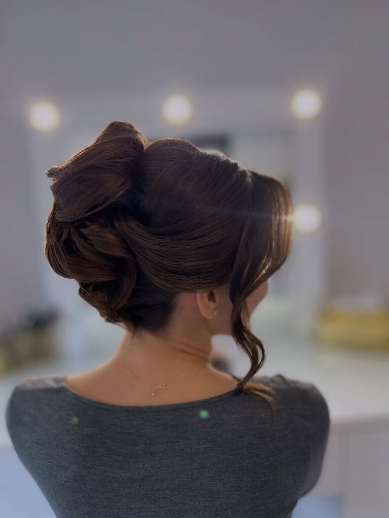 Voluminous curly updo with soft structure and loose face framing curls.