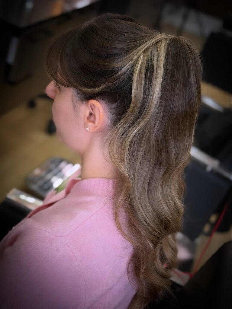 High ponytail with smooth top and soft wavy lengths.