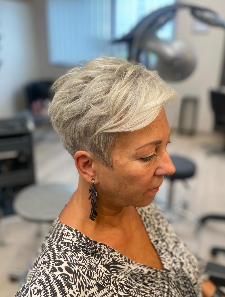 Short silver pixie haircut with textured top and sweeping side bangs.