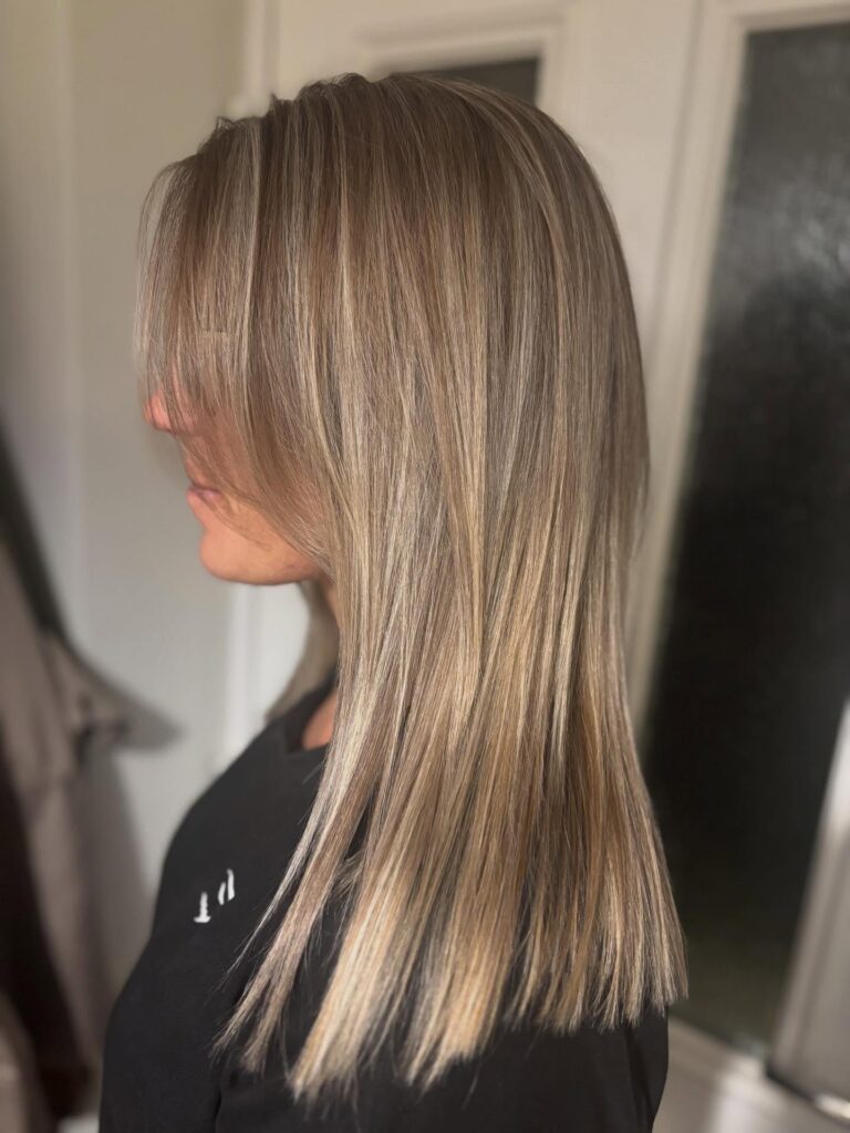 Straight long bob with long side swept bangs and cool toned blonde color.
