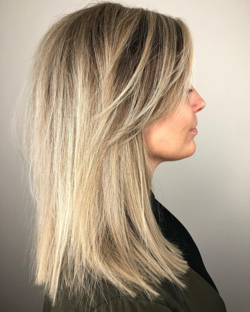 Shoulder length blonde layered hair with soft side swept face framing pieces.