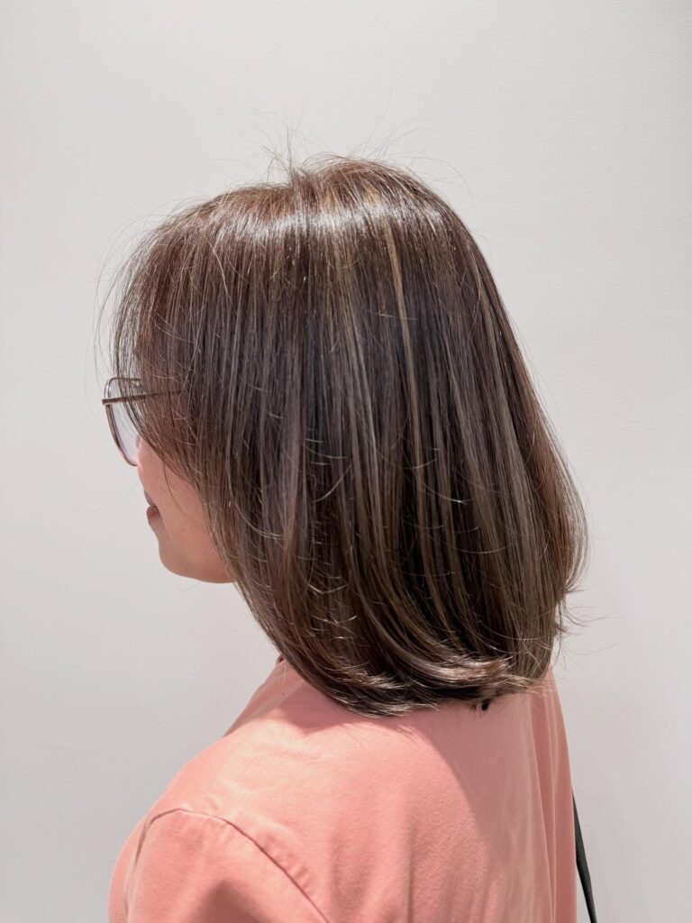 Medium length brunette layered bob with subtle face framing bangs and smooth curved ends.