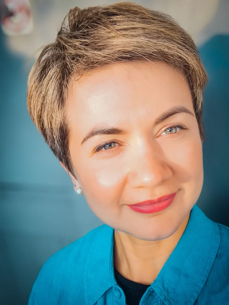 A woman with a short side swept tomboy haircut in warm brown tones with soft volume on top.