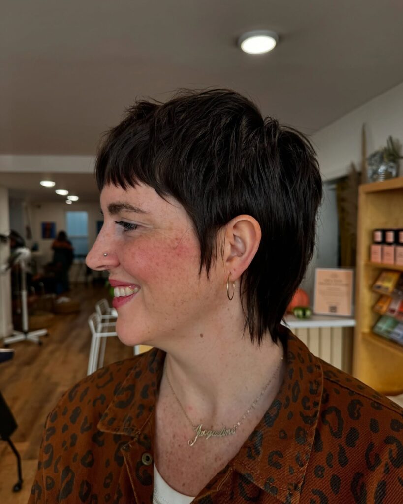 A woman with a shaggy tomboy haircut with choppy layers and a slightly longer back.
