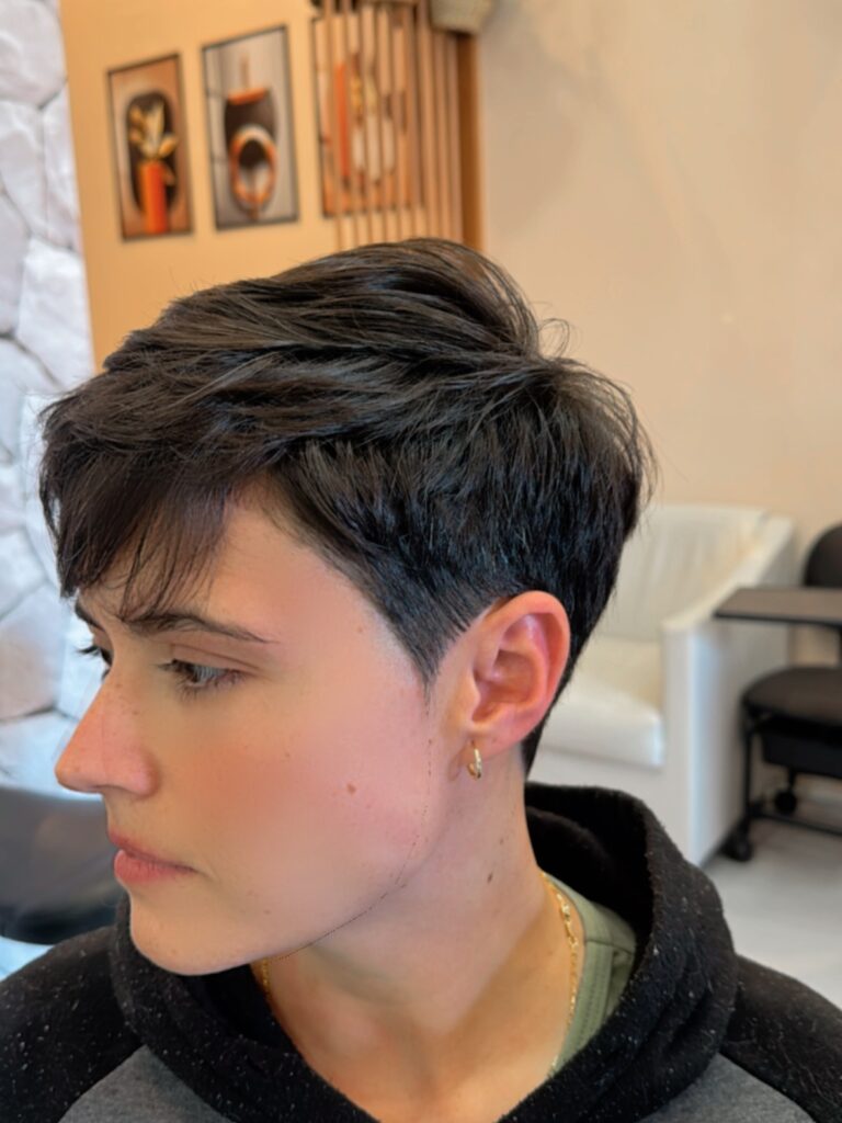 A woman with a short tomboy pixie haircut featuring a side swept top and subtle undercut.