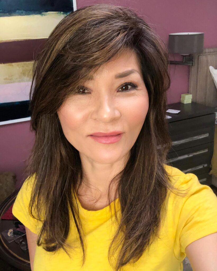 Medium length layered brown hairstyle with soft volume and side swept bangs.