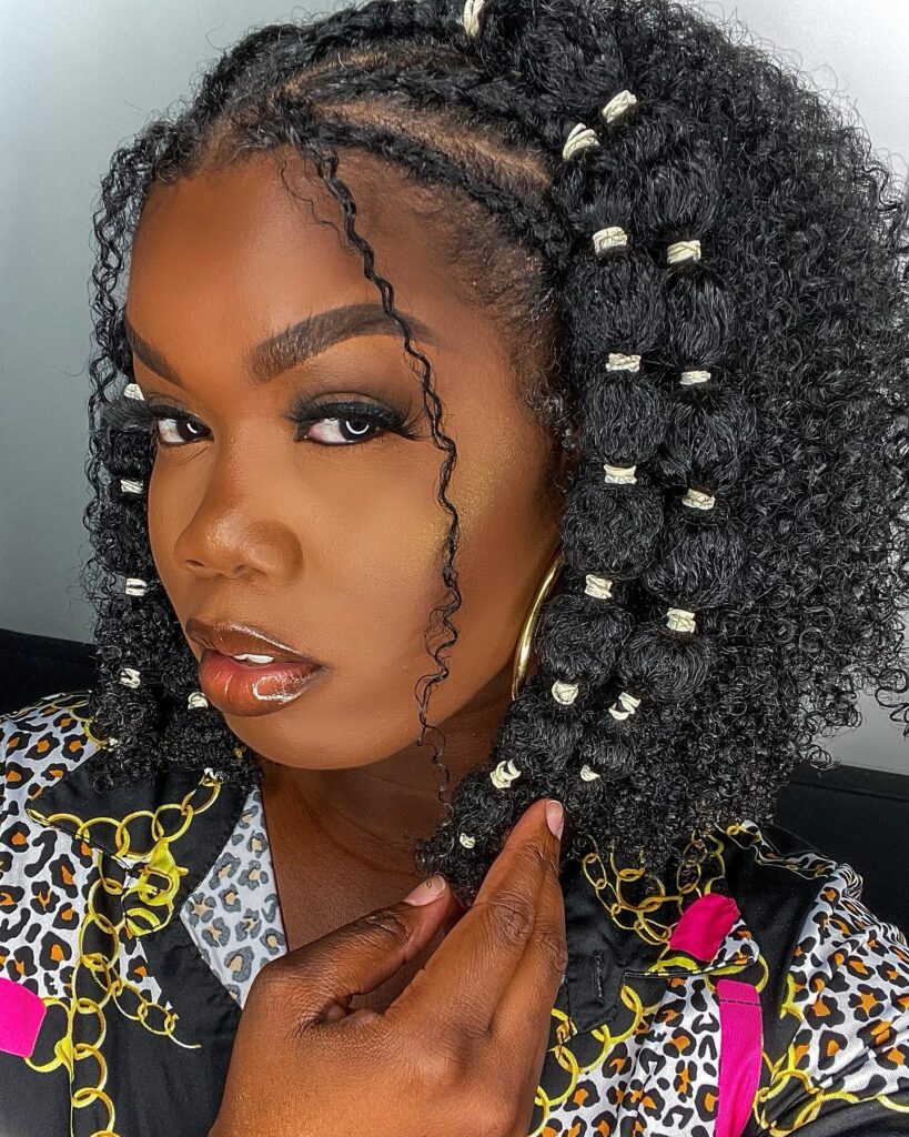 Rubber band bubble braid style on one side with voluminous natural curls on the other.