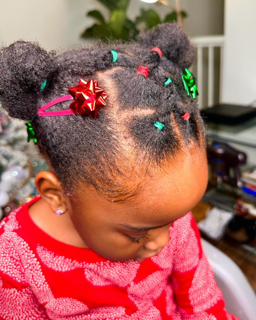 Natural hair styled with rubber band sections, mini puffs, and decorative clips with two buns.