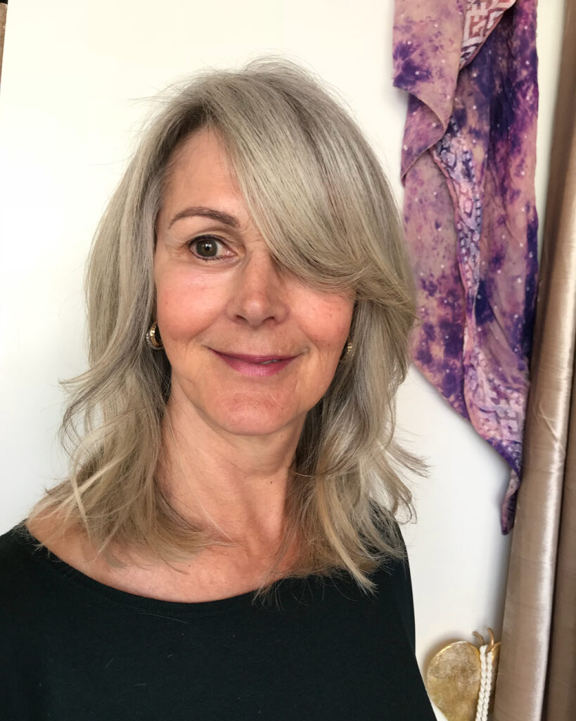 Shoulder length silver layered hair with feathered ends and side swept bangs.