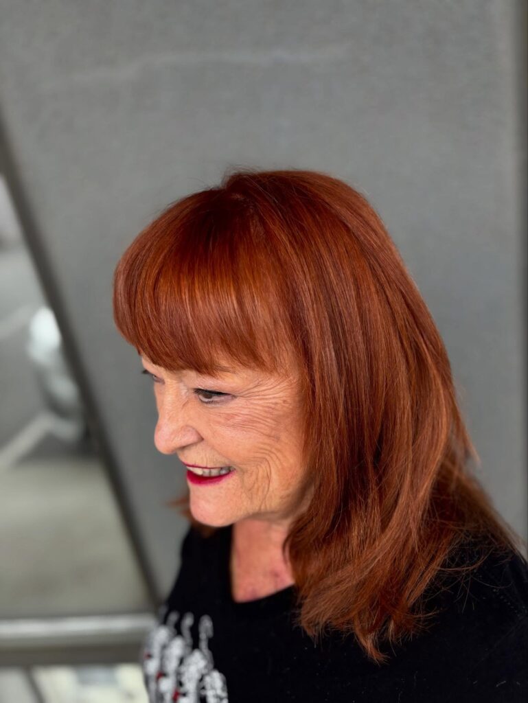 Shoulder length straight copper hair with full rounded bangs.