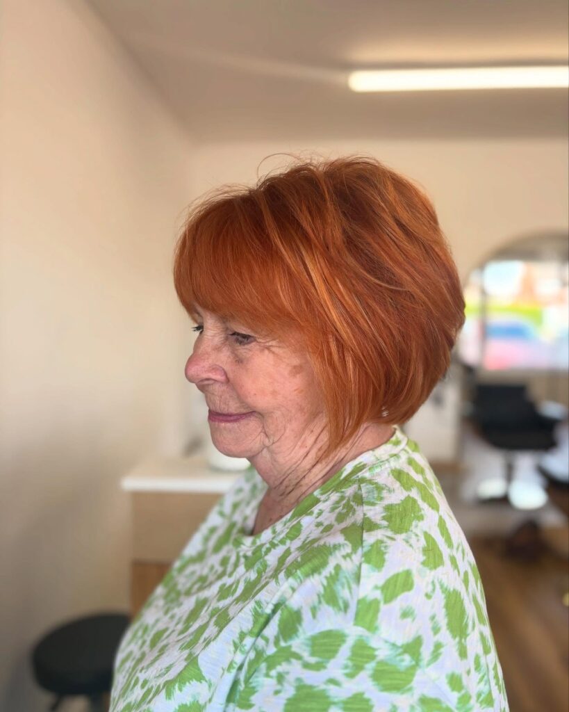 Chin length sleek copper bob with full straight bangs.