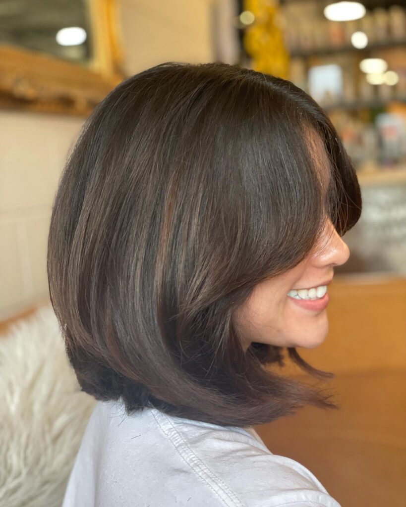 A voluminous rounded brown bob with side swept bangs and softly curved ends