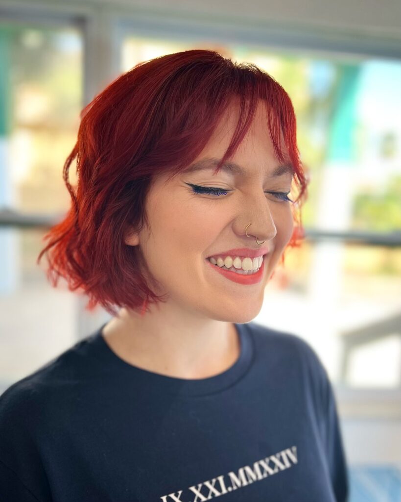 A short wavy red bob with piecey bangs and soft natural texture