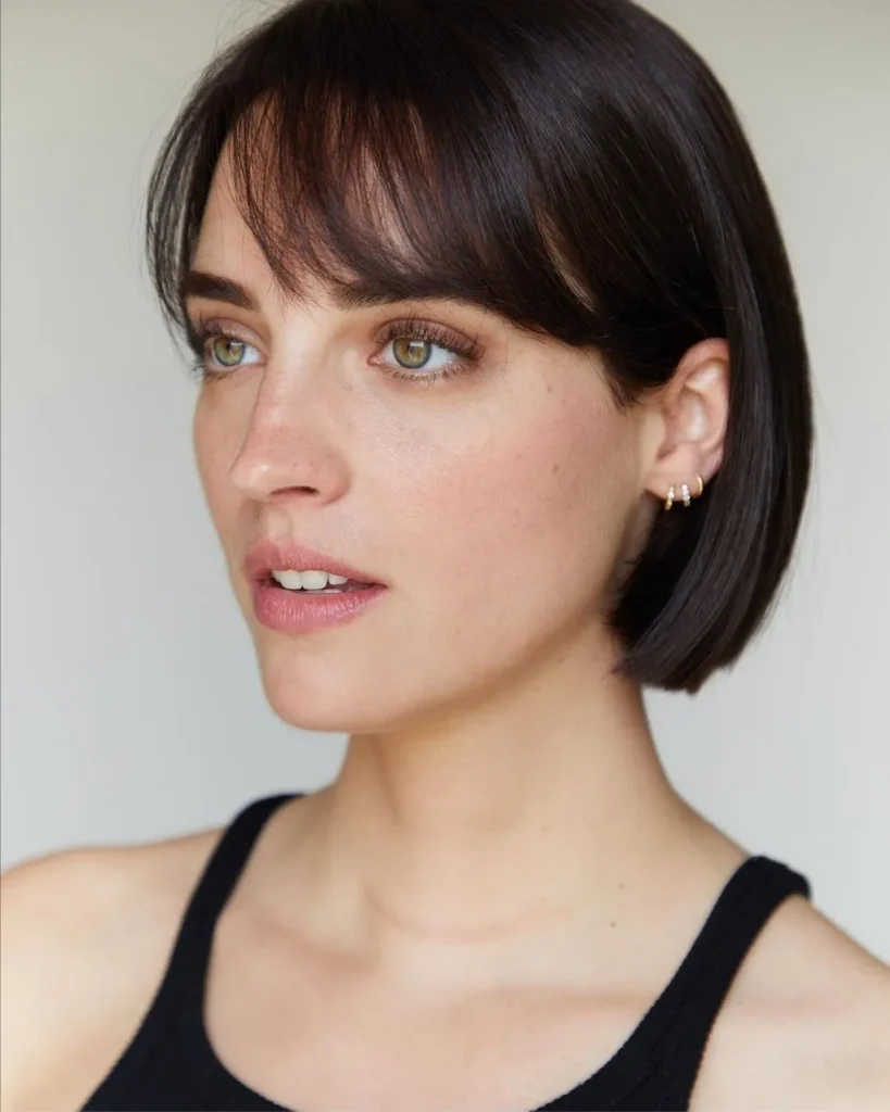 A sleek chin length brunette bob with soft curtain bangs and a smooth polished finish
