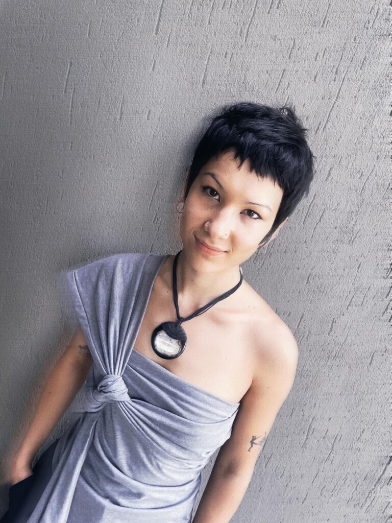 A woman with a short tomboy crop featuring a high fade and a neatly textured dark top.