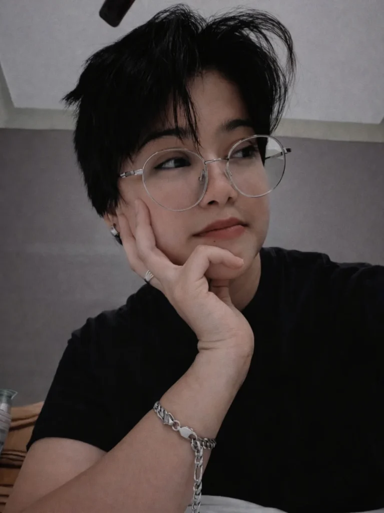 A woman with a short messy tomboy crop featuring natural volume and a soft uneven fringe in black hair.