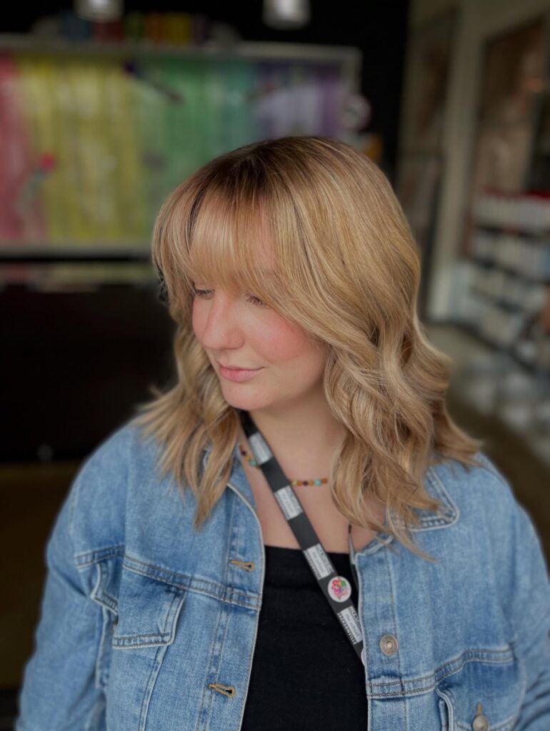 A blonde shoulder-length lob with soft waves and a full fringe.