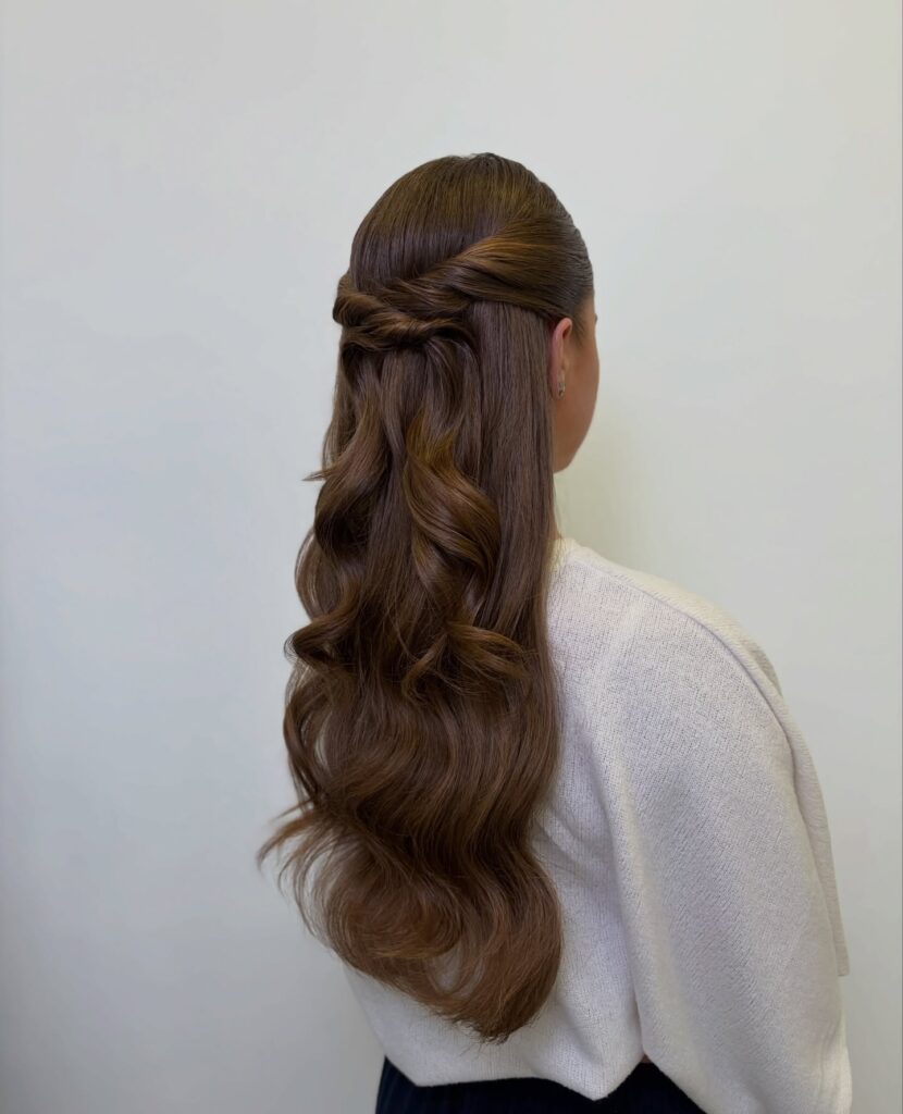 Long brunette wavy hair styled in a braided twist half up half down hairstyle with soft waves.