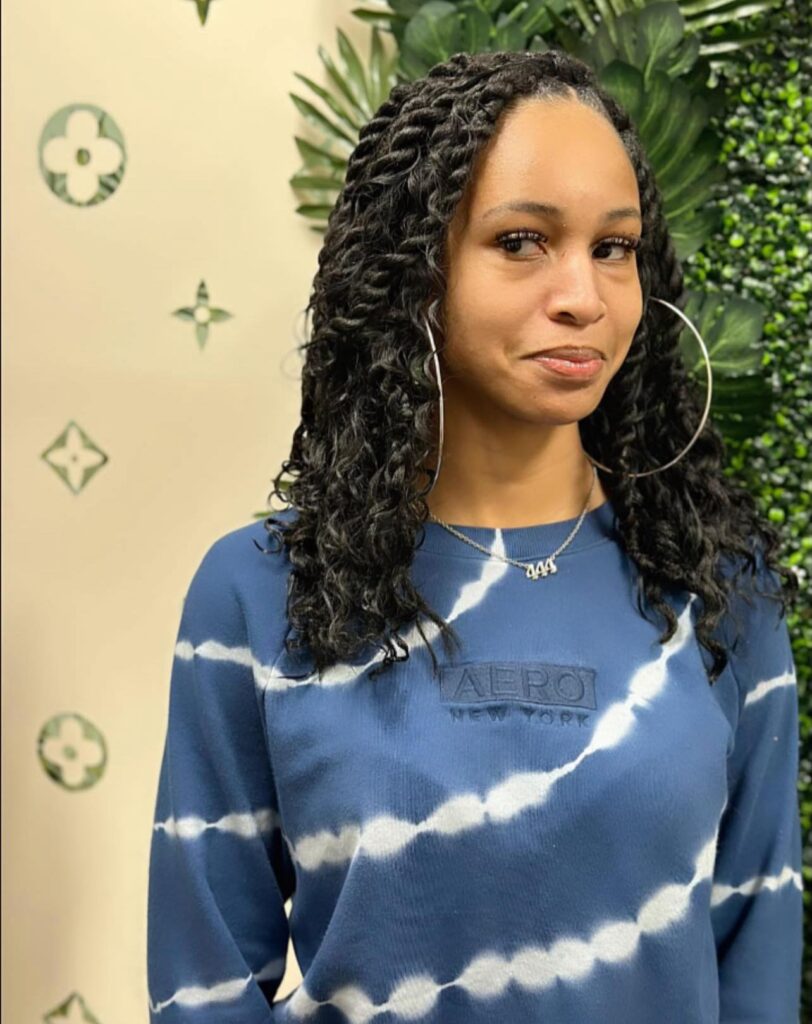 A woman with a shoulder length twist out hairstyle featuring soft defined curls and a natural side part.