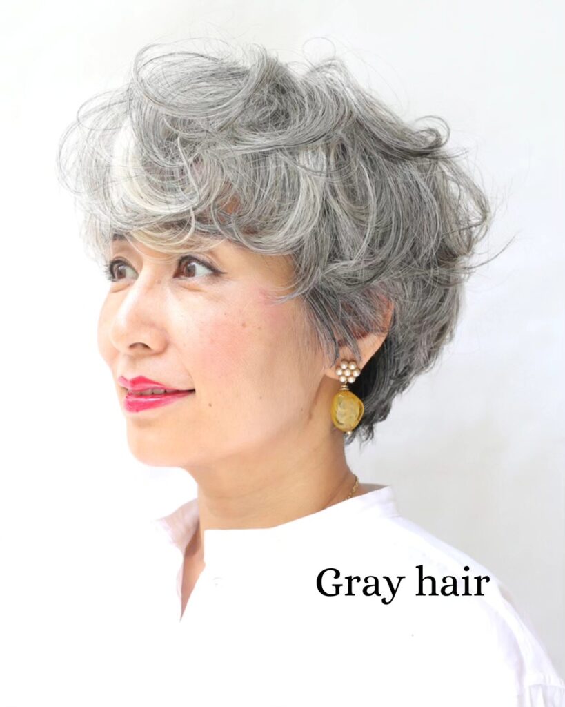 Short curly gray bob with full soft bangs and voluminous texture on a mature woman.