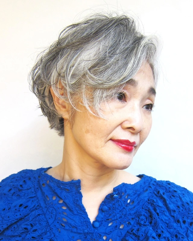 Short feathered gray bob with side swept bangs and soft layered volume.