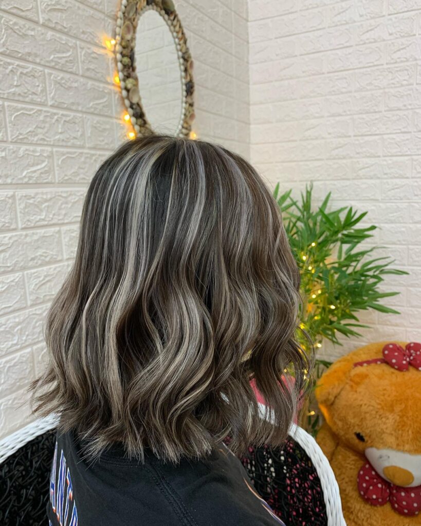 Medium length wavy gray bob with soft blended tones and natural shine from the back view.