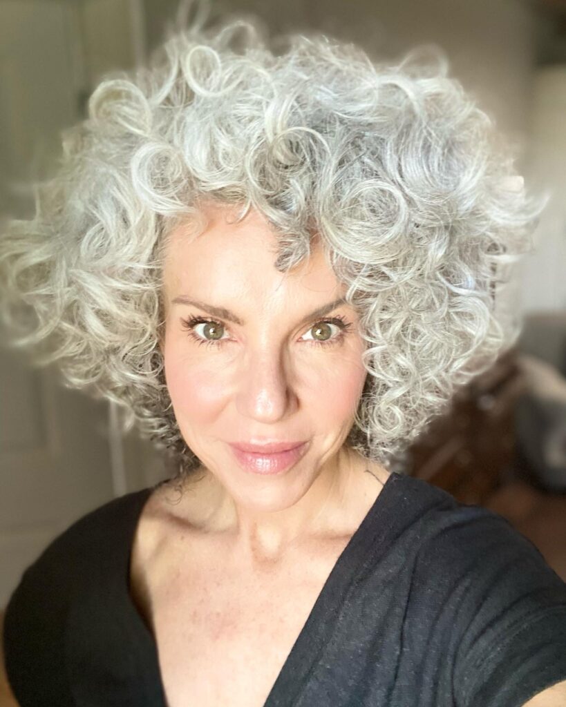 Voluminous curly gray bob with tight defined curls and bright silver color.